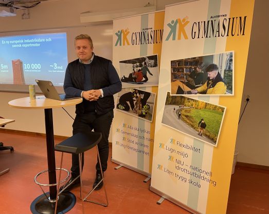 H2GS Johannes Granström står vid föreläsningsdator framför rollups från Älvsbyns gymnasium.