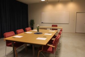Konferensrum med bord, stolar och whiteboard.