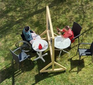 Besök vid en av Nyberga äldreboendes plexiglasskärmar