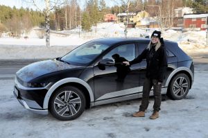 En kvinna står utanför sin elbil utomhus