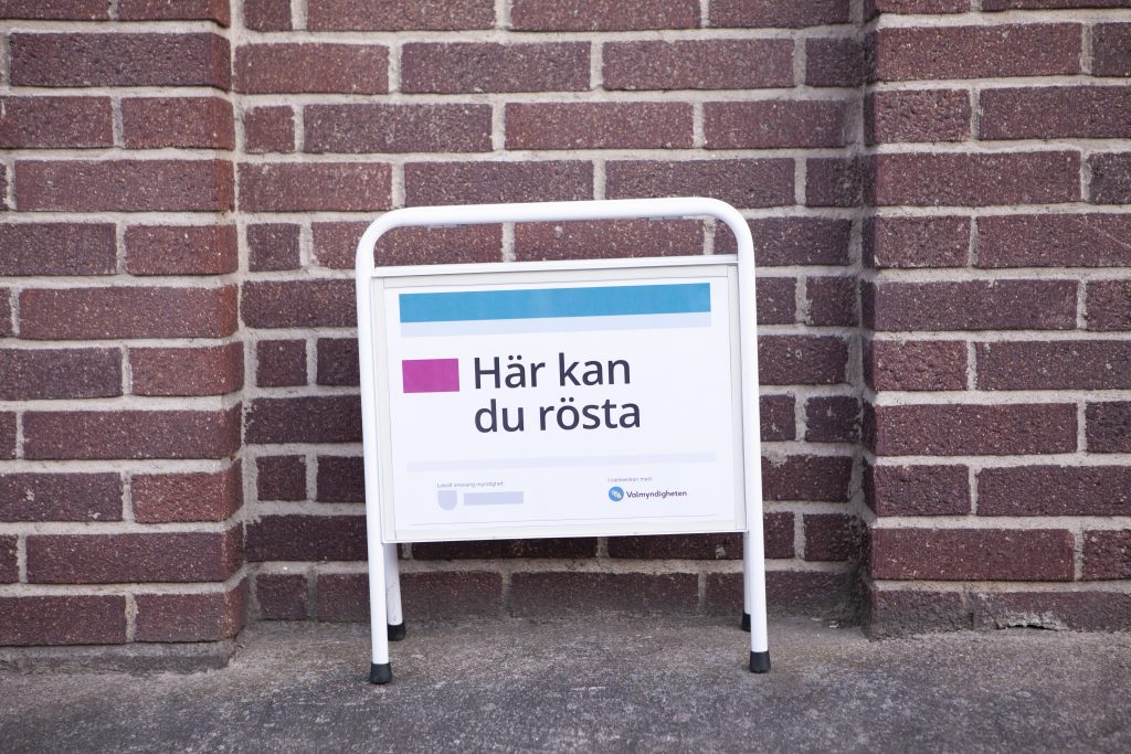 bilden visar bakgrunden är en tegelvägg och en gatupratare med texten Här kan du rösta.