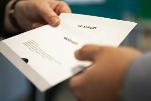 Bilden visar Röstmottagare lämnar tre valkuvert till en väljare.