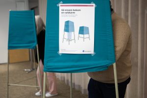 Bilden visar väljare som står bakom valskärmar