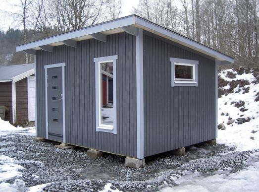 Mörkgrå bastubyggnad med ljusgrå knutar.