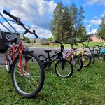 Bild på flertalet barncyklar uppradade på en gräsmatta.