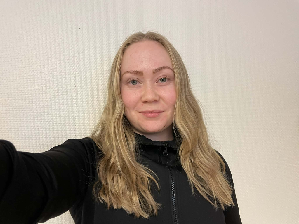 Bild på Malin Persson framför en vit vägg.