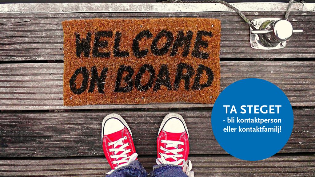 Ett par röda skor står vid en dörrmatta där det står välkommen ombord.