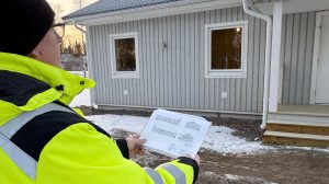 En man håller upp en ritning och jämför med ett hus.