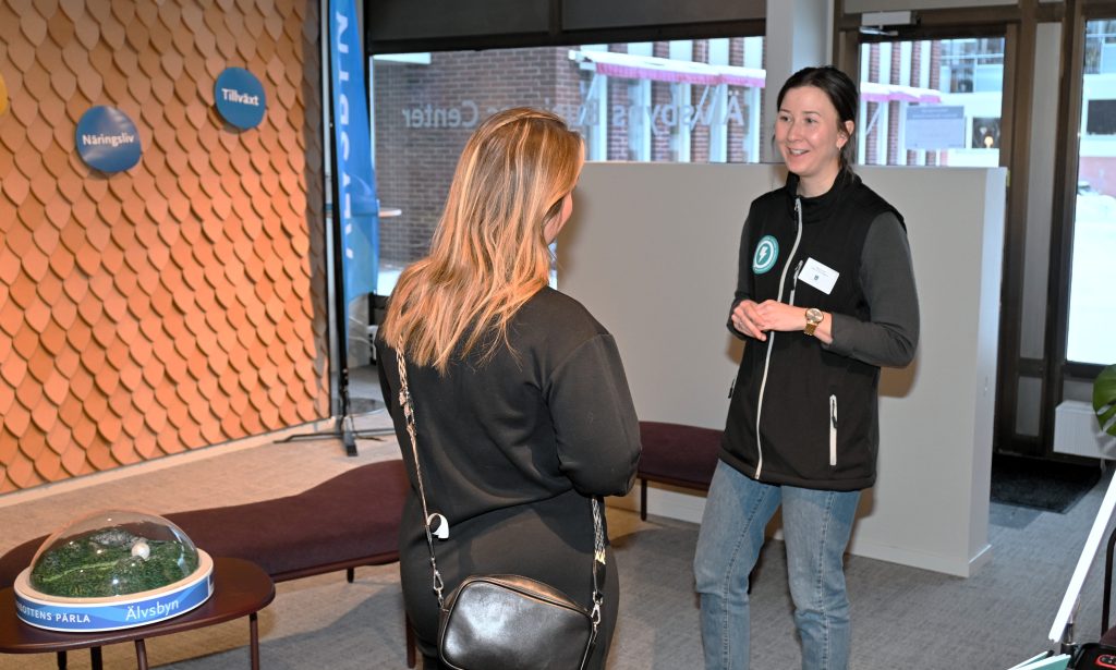 Två personer står och pratar med varandra.