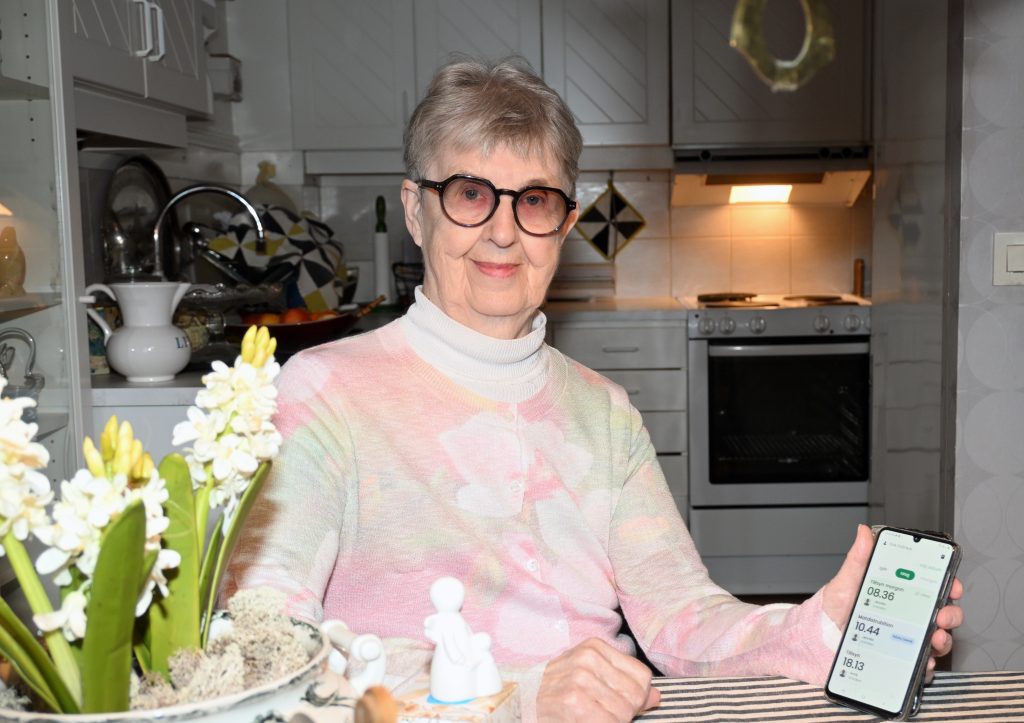 Eva Ovefalk håller i sin telefon som visar relate-appen.