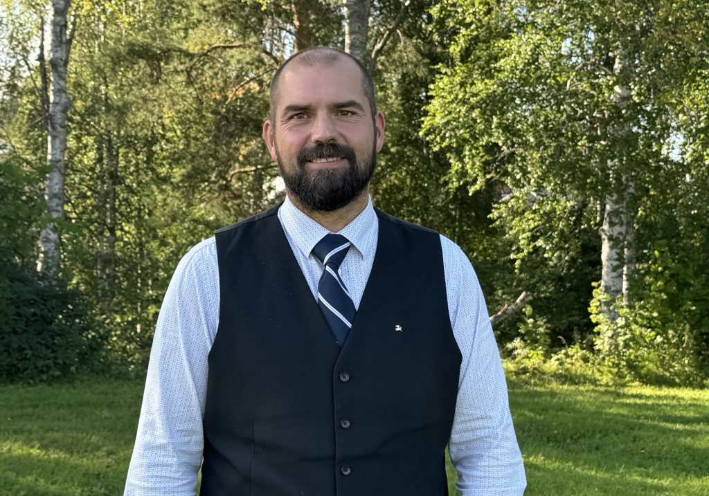 Jonas Wallin med en grön gräsmatta och gröna träd.