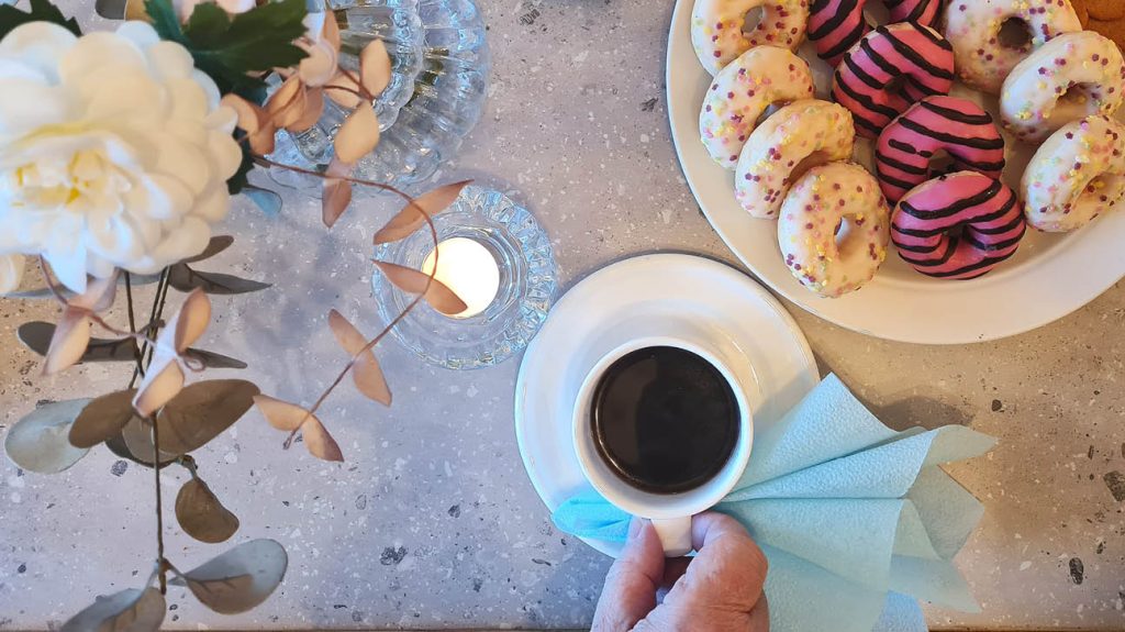 Bilden visar ett fikafat, kaffekopp och blommor