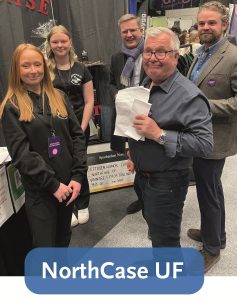 Bild på två tjejer och ett par män som står vid en monter med texten NorthCase UF.
