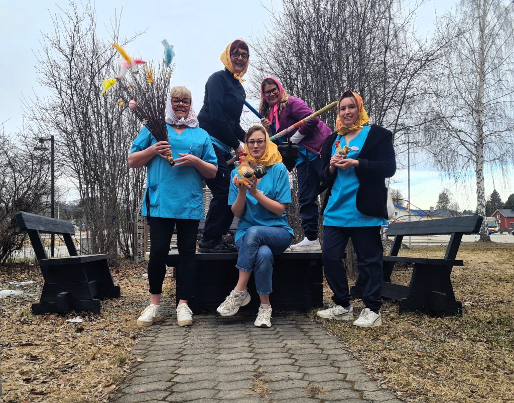 Personer står vid en eldstad, utklädda till påskhäxor.