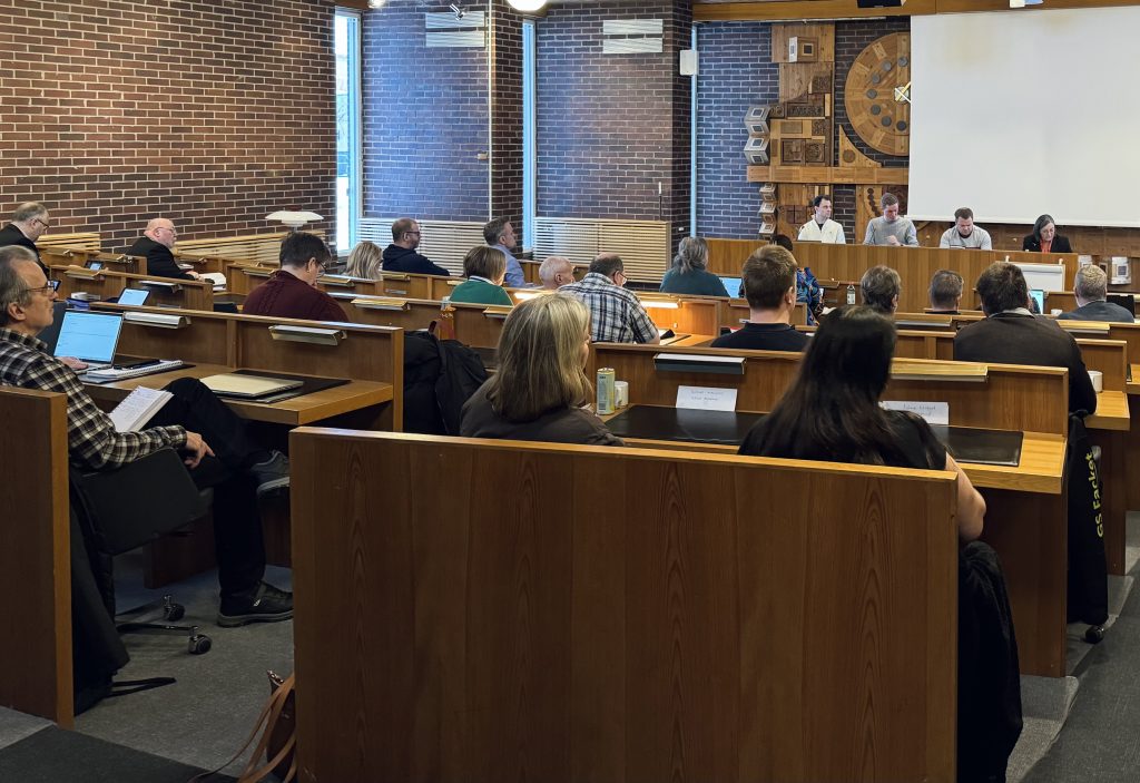 Bilden visar representanter från kommunfullmäktige som sitter i kommunfullmäktigesalen.